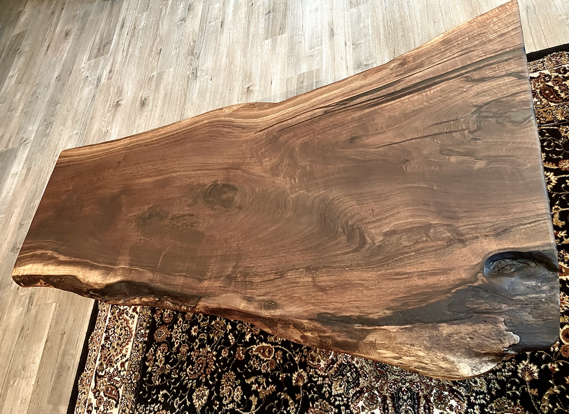 Top-down view of large live edge black walnut coffee table, highlighting natural wood grain, and live edge details. Handcrafted live edge walnut coffee table styled in a modern living room with a cozy, rustic aesthetic. Detailed view of live edge walnut wood grain, showing natural  color variations, and organic patterns. Large live edge black walnut coffee table made from walnut featuring unique grain patterns and a smooth, polished surface. Rustic and modern design.