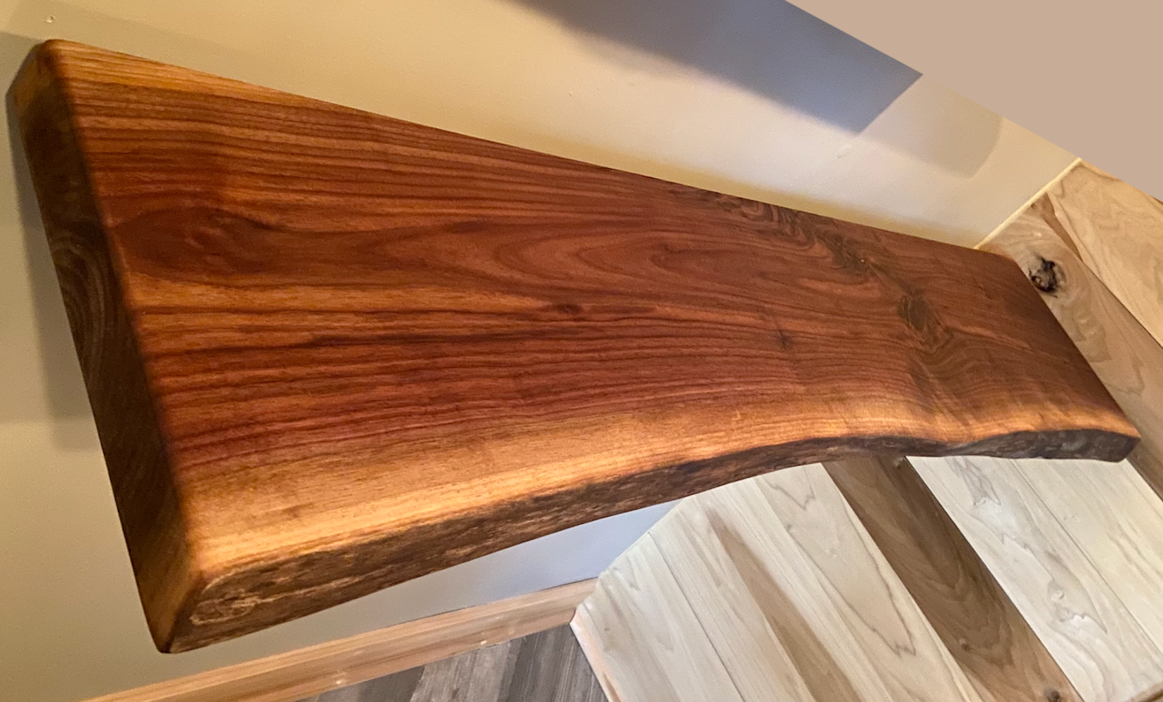 Live edge walnut floating shelf mounted on a light-colored wall, showcasing natural grain, dark tones, and organic edge detail