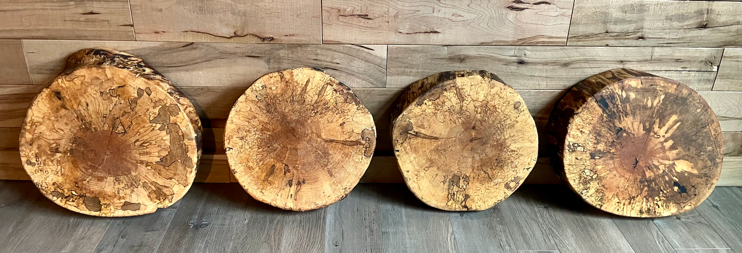 Four wooden stools with a rustic finish arranged in a row against a wooden wall.