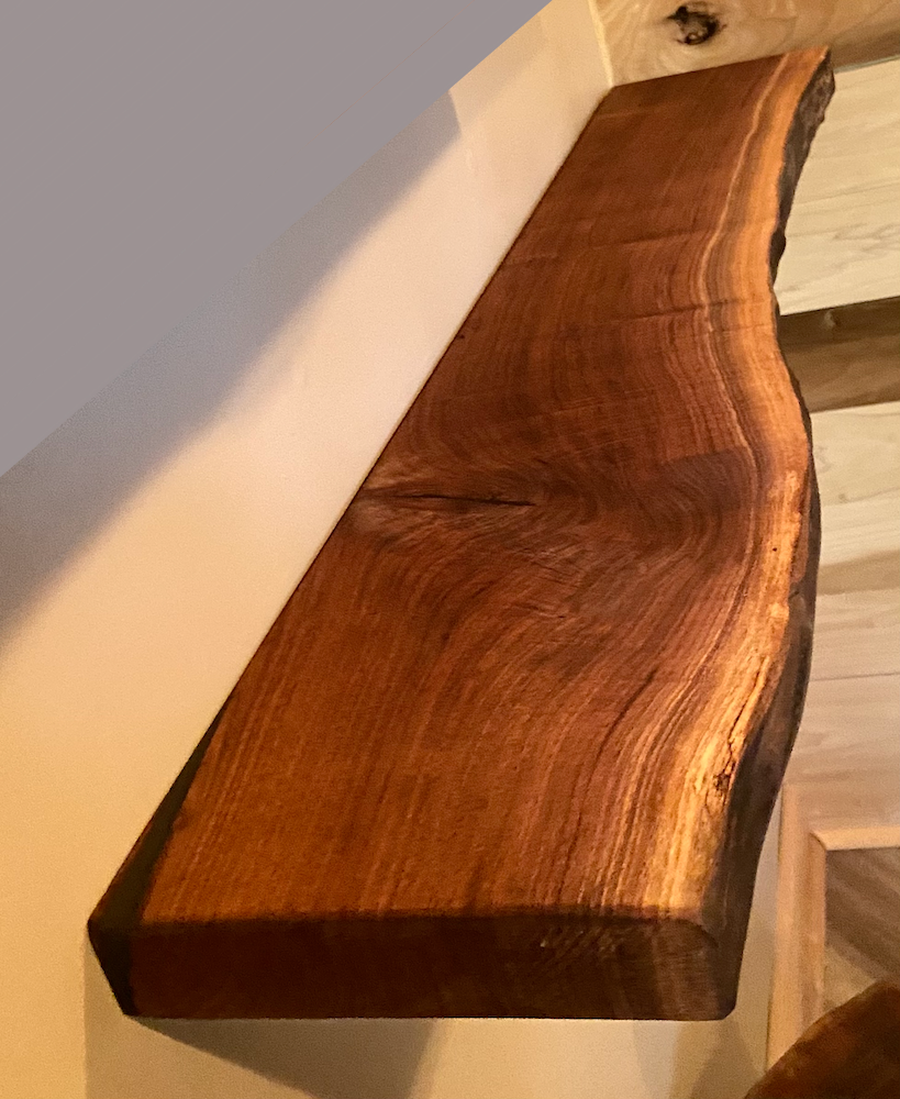 Wooden live edge walnut shelf with a natural grain pattern on a light-colored floor.
