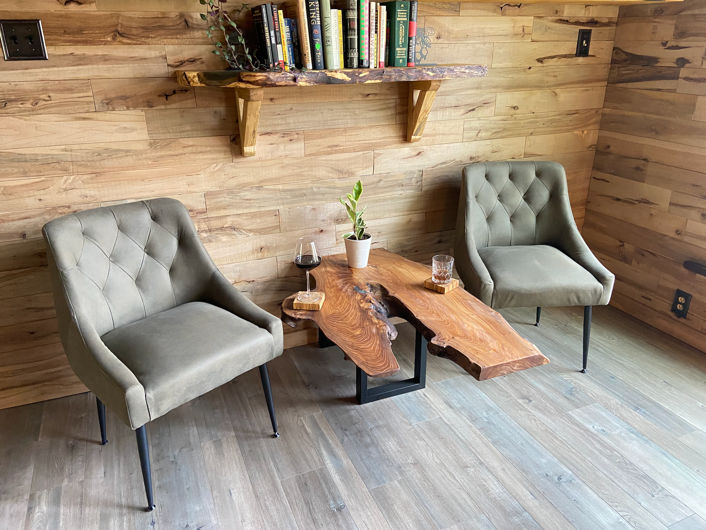 Modern interior with two gray chairs and a wooden chestnut coffee table against a wooden wall that has a live edge maple shelf.