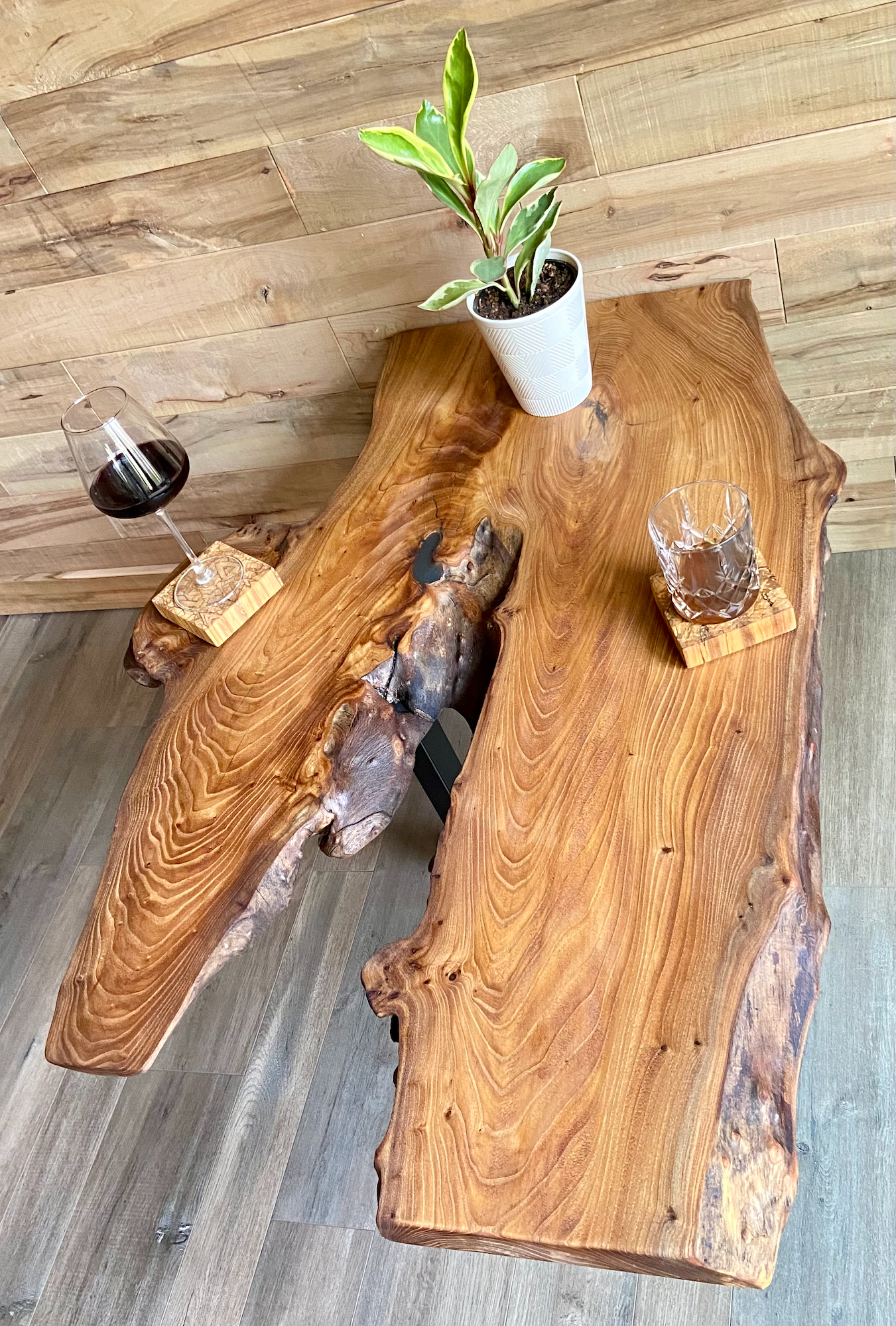 Wooden rustic coffee table from live edge chestnut with a plant and glasses.