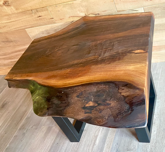 Wooden side table with a natural edge design on a wooden floor