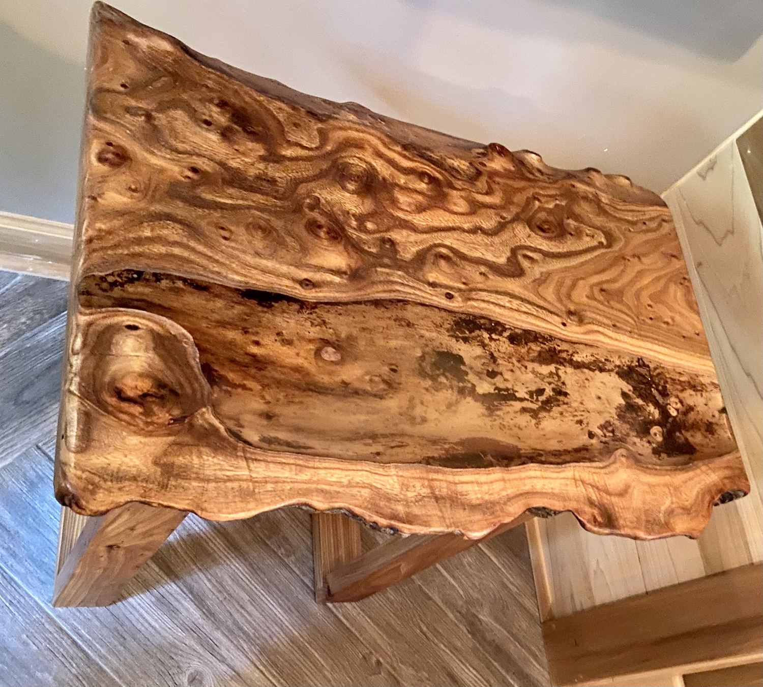 Wooden live edge chestnut coffee table with a natural, wavy grain pattern on a wooden floor.