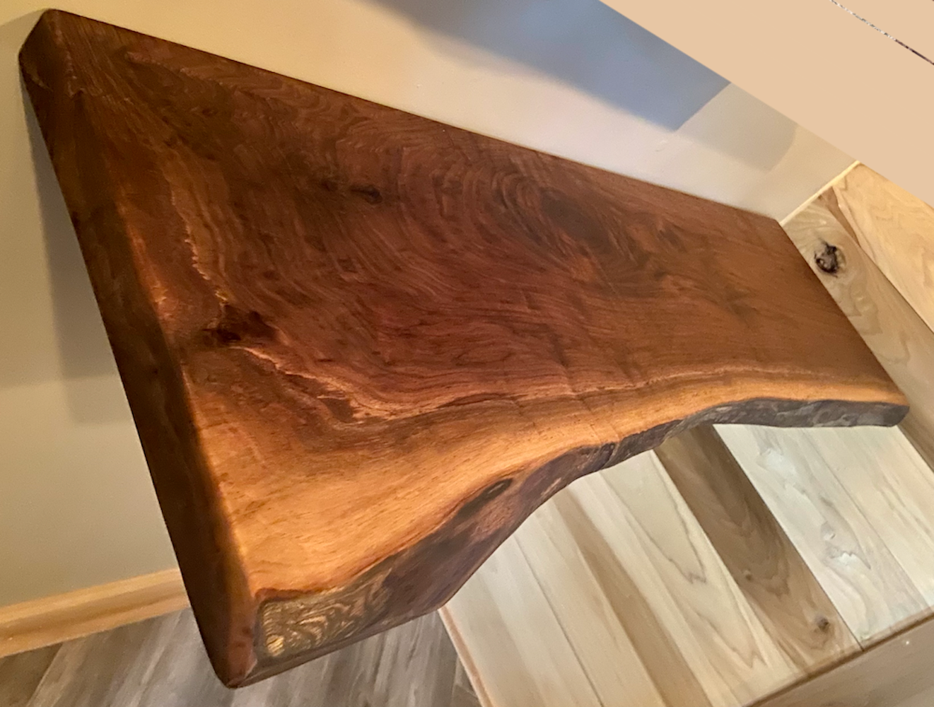 Live edge walnut floating shelf mounted on a light-colored wall, showcasing natural grain, dark tones, and organic edge detail
