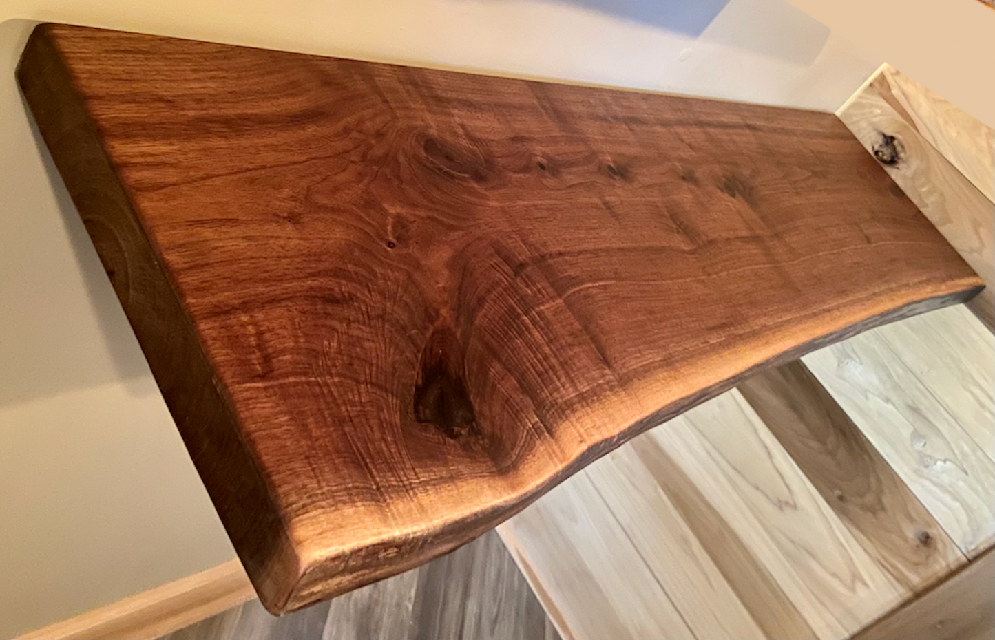 Live edge walnut floating shelf mounted on a light-colored wall, showcasing natural grain, dark tones, and organic edge detail