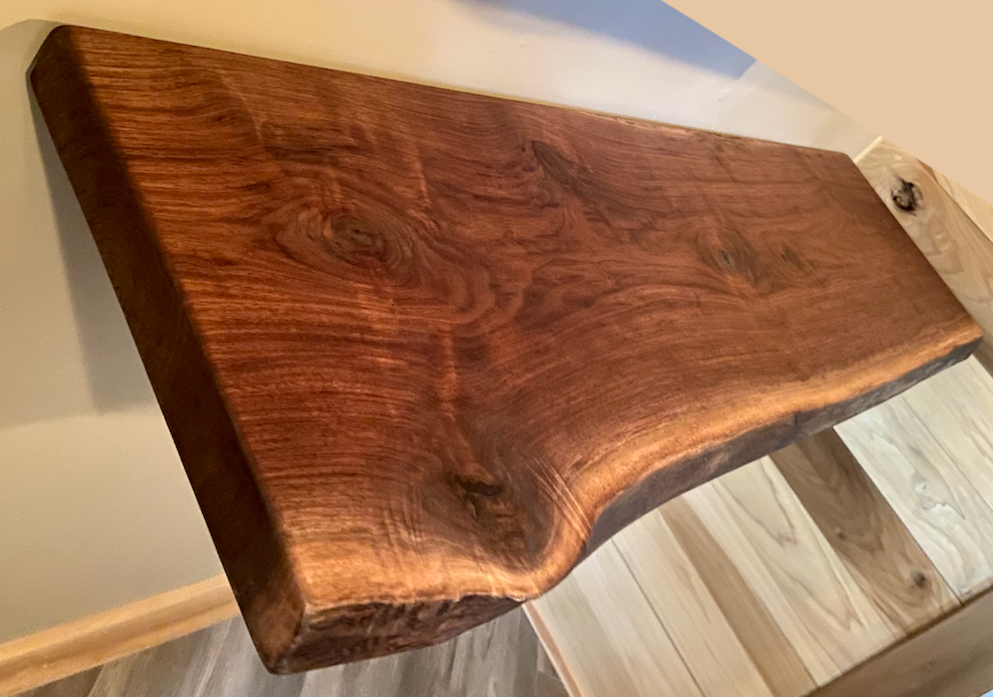 Live edge walnut floating shelf mounted on a light-colored wall, showcasing natural grain, dark tones, and organic edge detail