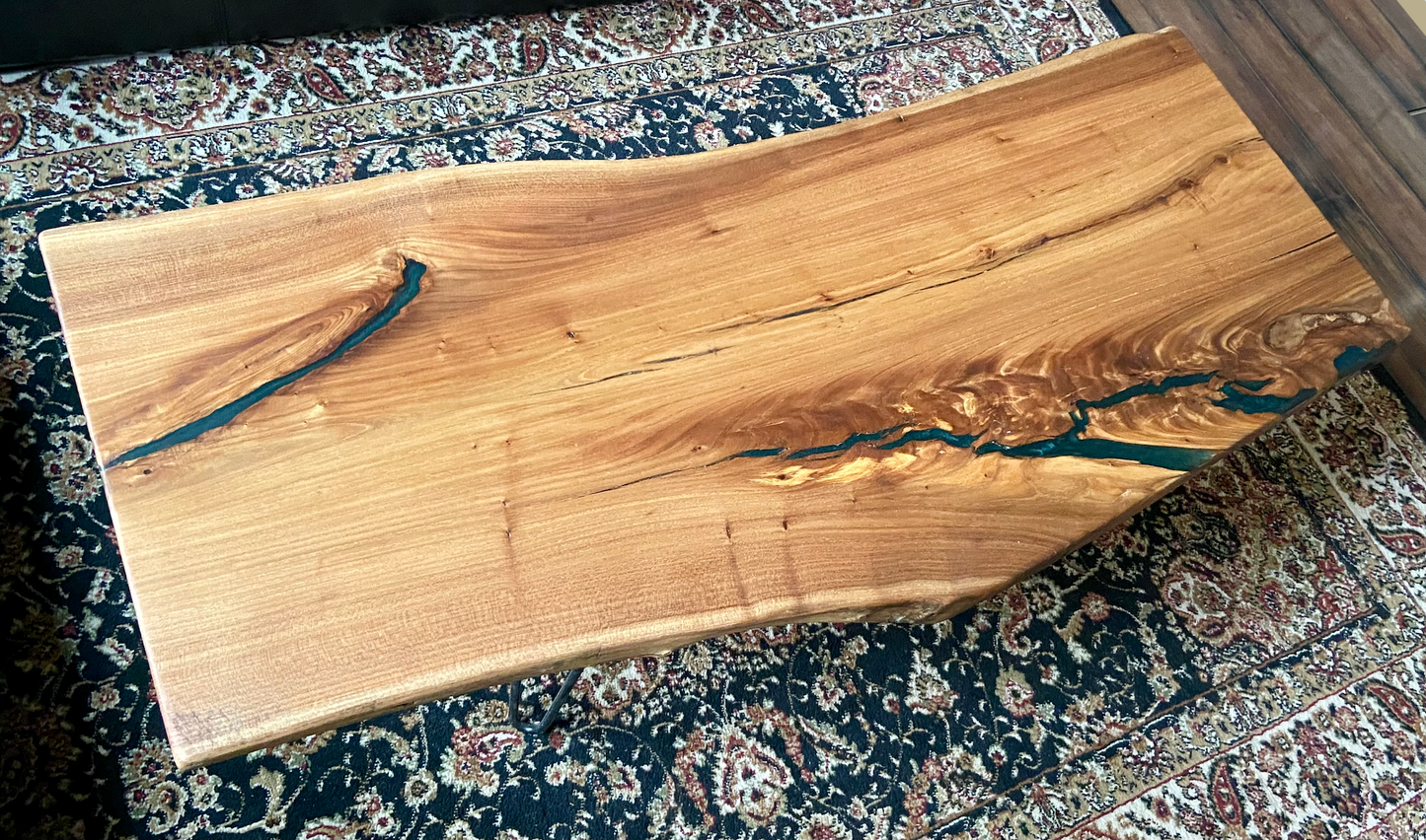 Live edge chestnut wood coffee table with green epoxy resin in cracks on a patterned rug
