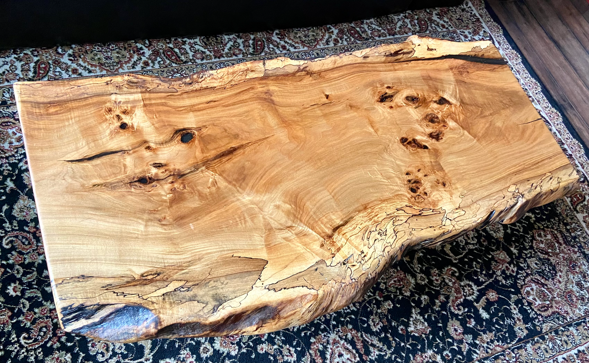 Live edge spalted ambrosia maple wood slab coffee table with a natural edge on a patterned surface