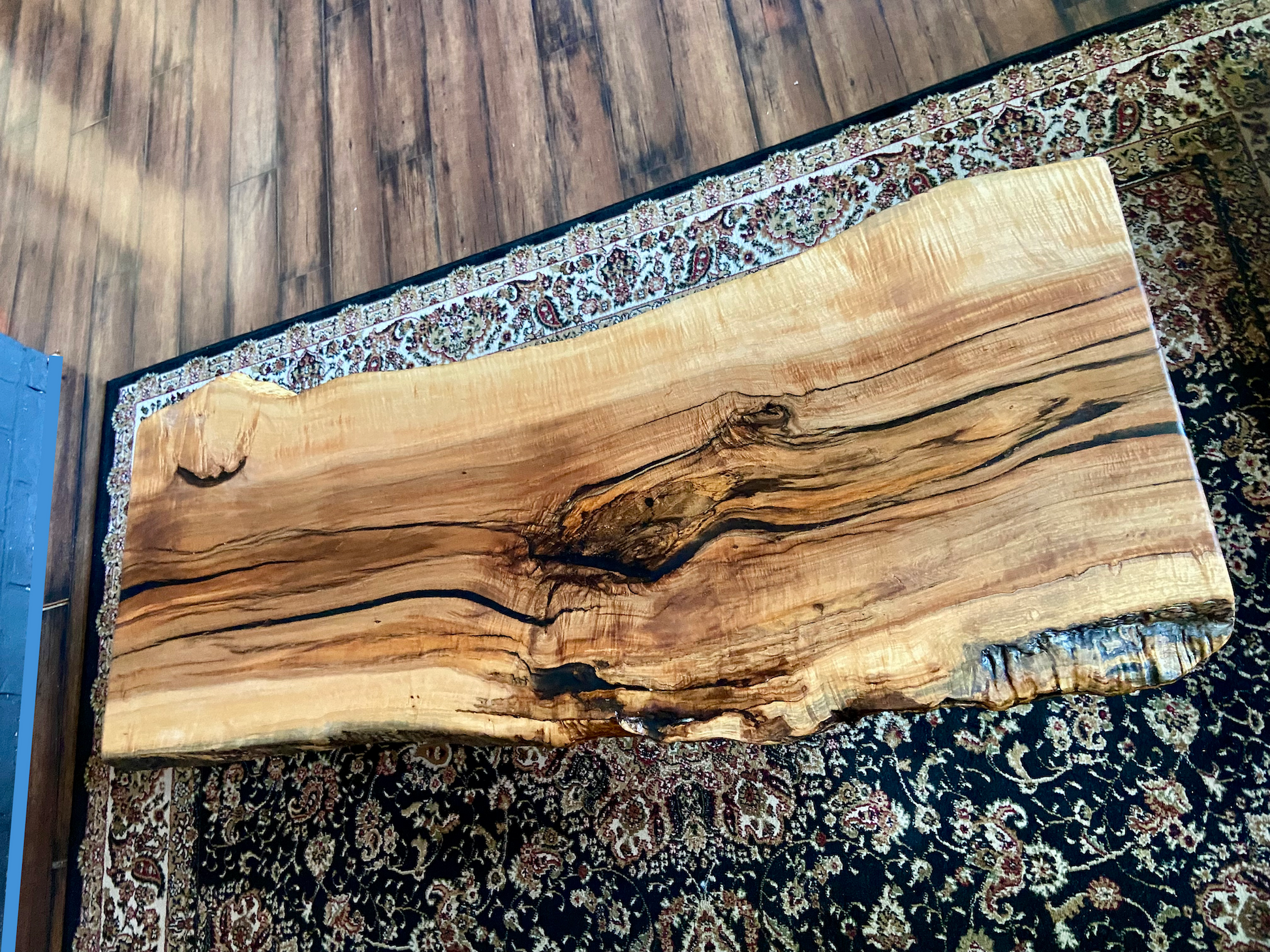 Live edge spalted ambrosia maple wood slab coffee table with natural grain and texture on a patterned rug