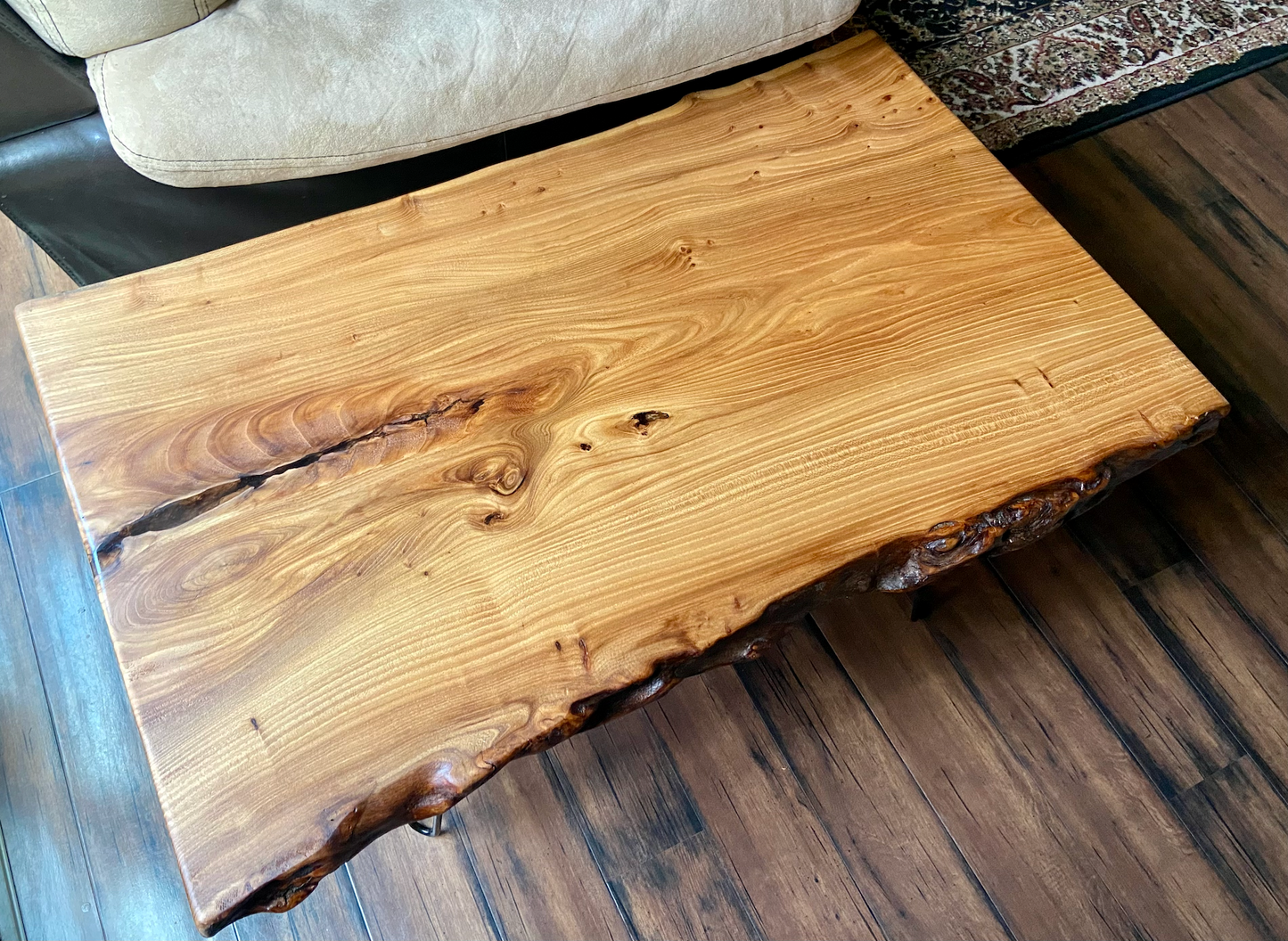 Live edge english chestnut wood slab coffee table with a natural edge design on a wooden floor.