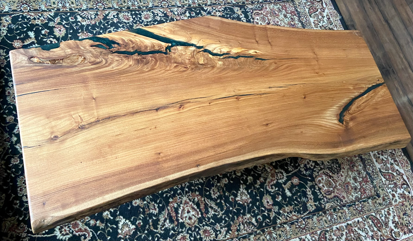 Live edge chestnut wood coffee table with a natural edge on a patterned rug. 