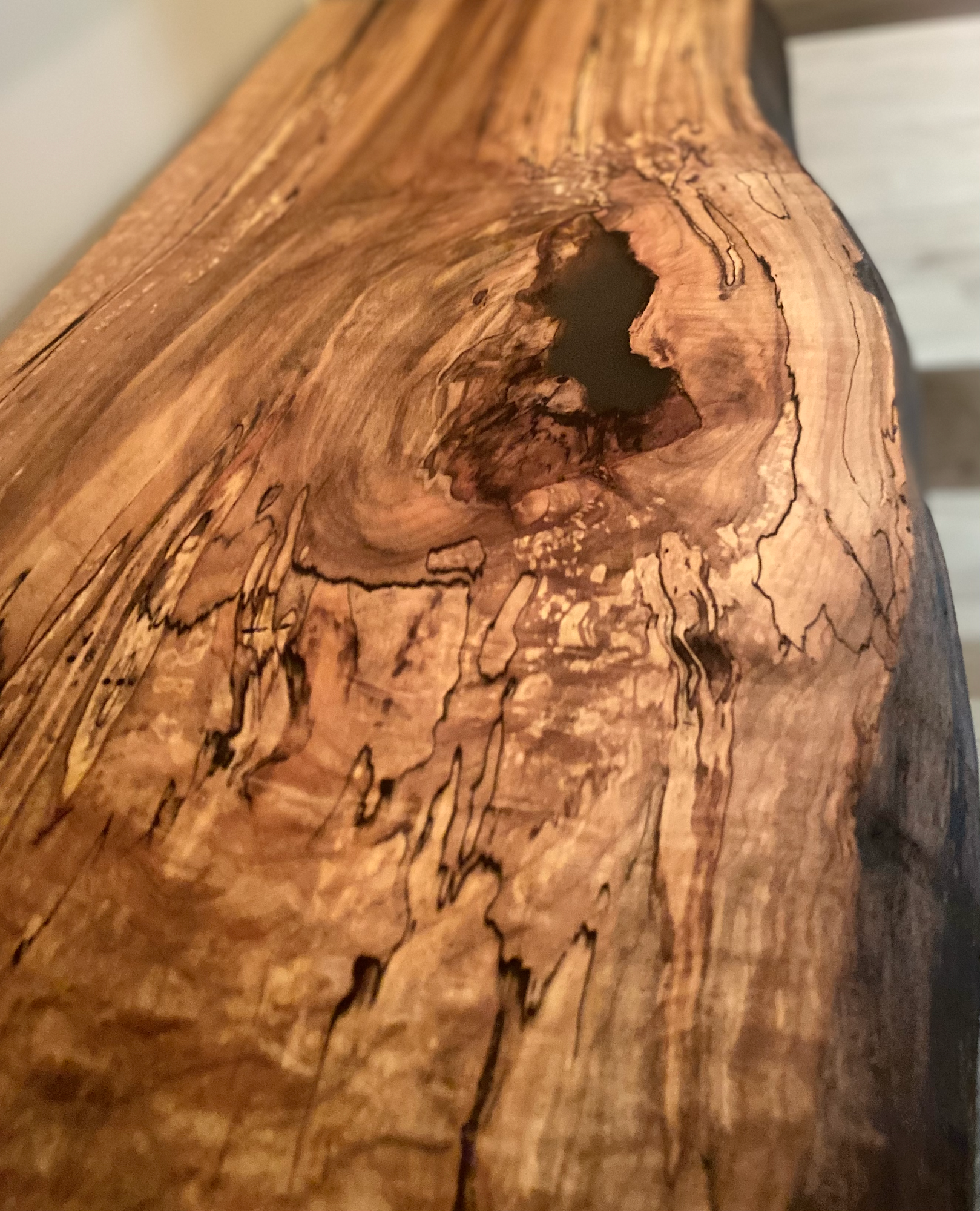 Close up of a spalted maple floating shelf with live edge, wall-mounted and handcrafted from natural wood.