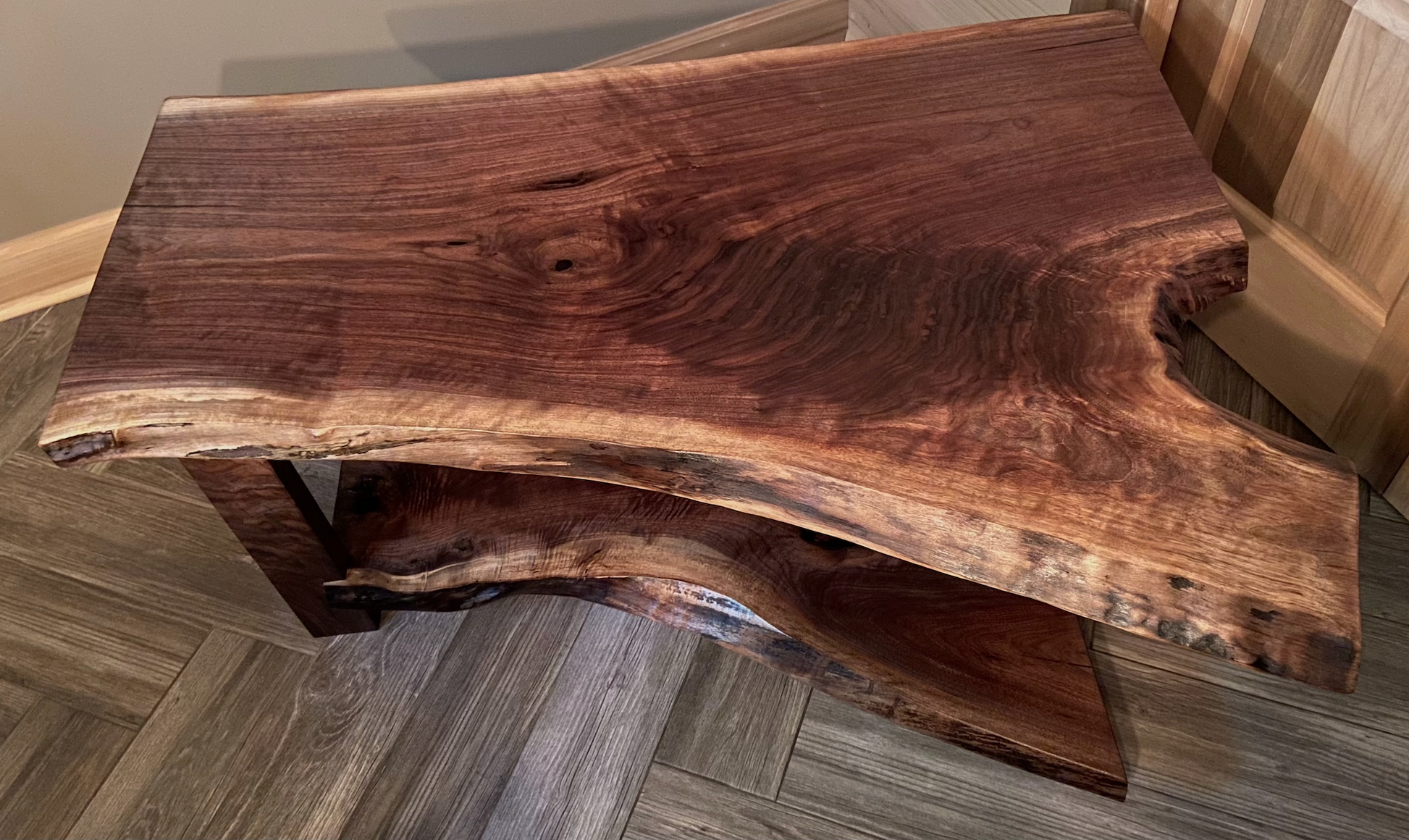 Live edge walnut wood slab coffee table with a natural, rustic finish on a wooden floor.