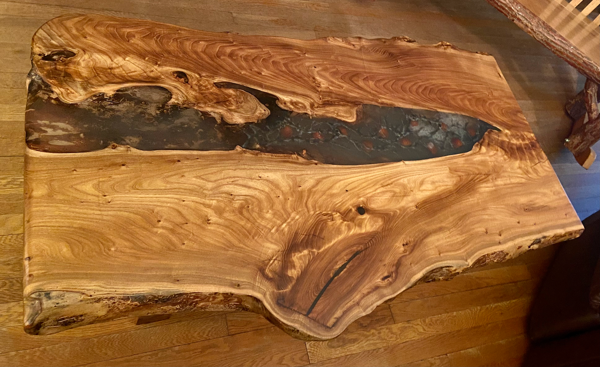 Wooden rustic live edge english chestnut coffee table with a natural, rustic finish on a wooden floor.