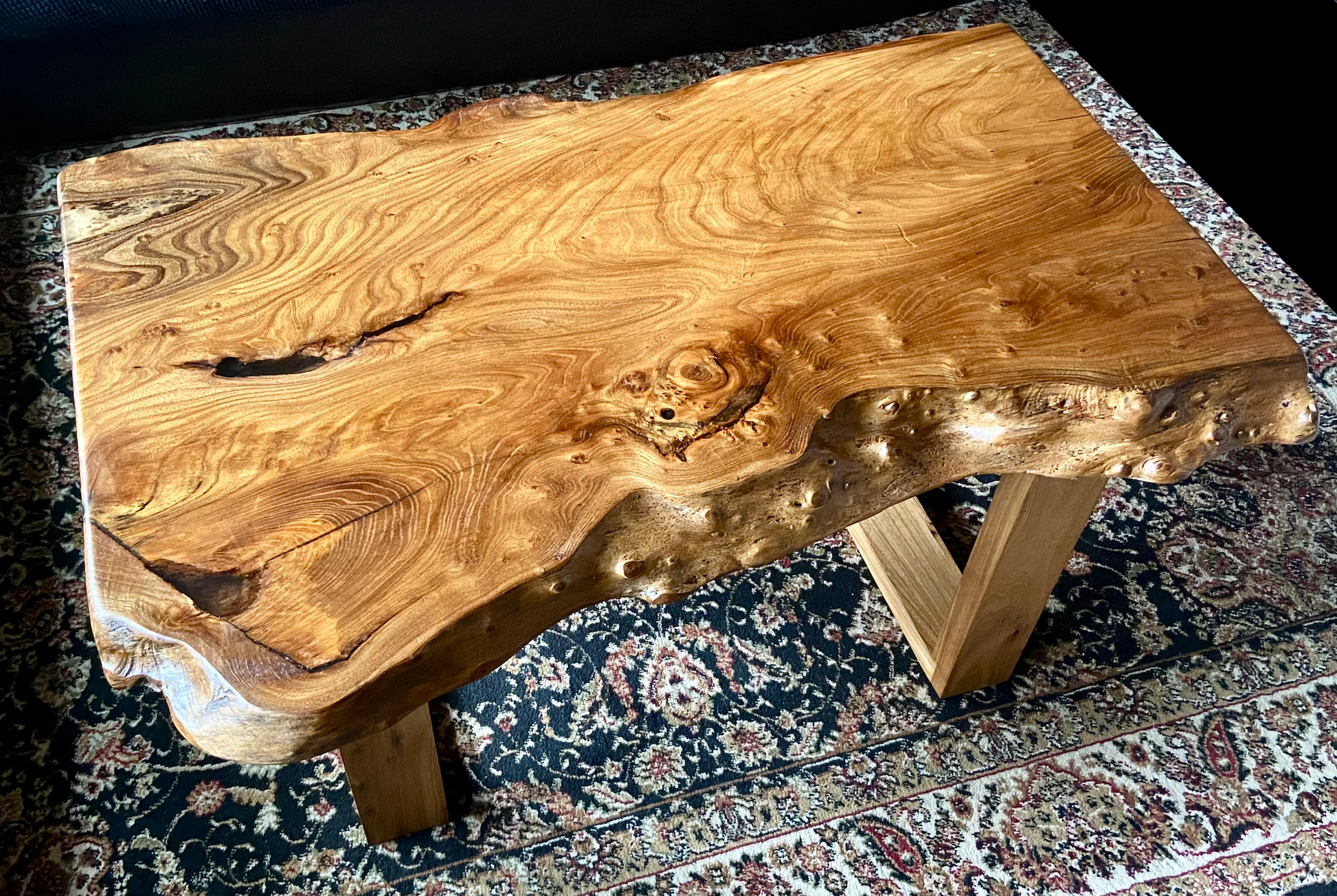 Live edge chestnut wood coffee table with a natural, rustic finish on a patterned rug.