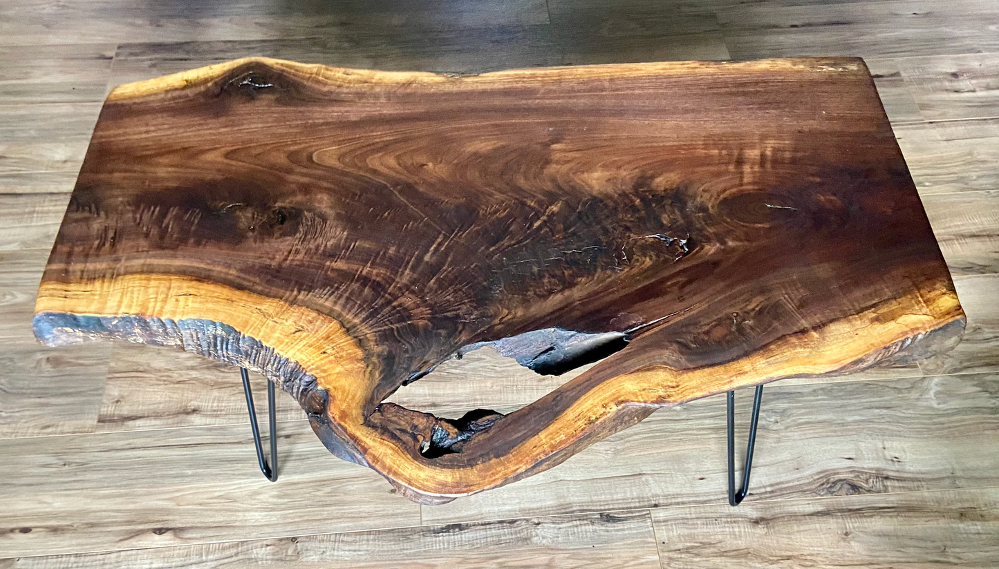 Live edge walnut wood slab coffee table with a natural edge on a wooden floor