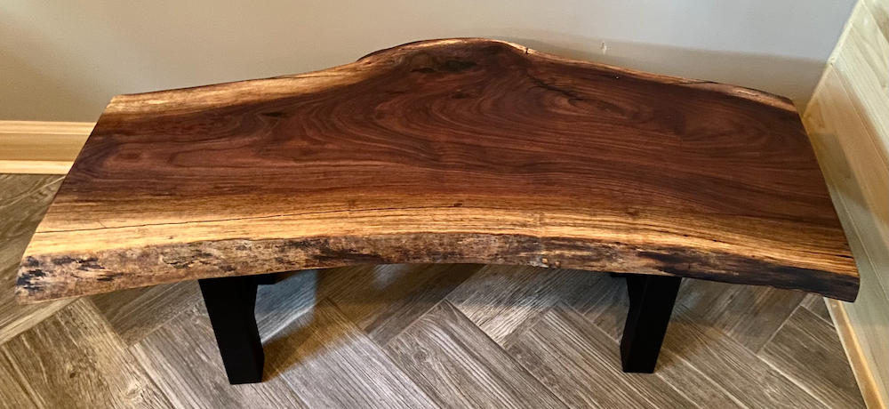 Live edge walnut wood slab coffee table with a natural finish on a wooden floor.