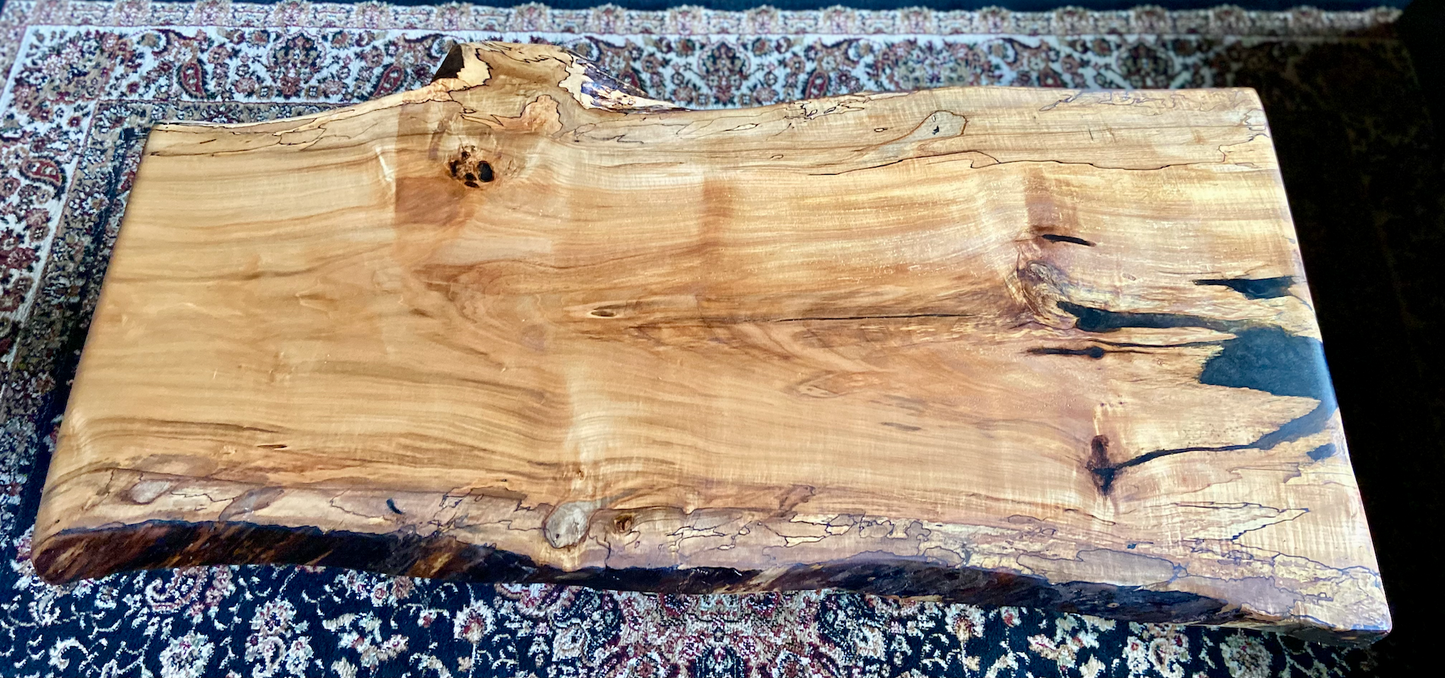 Live edge spalted ambrosia maple wood slab coffee table with a natural edge on a patterned surface