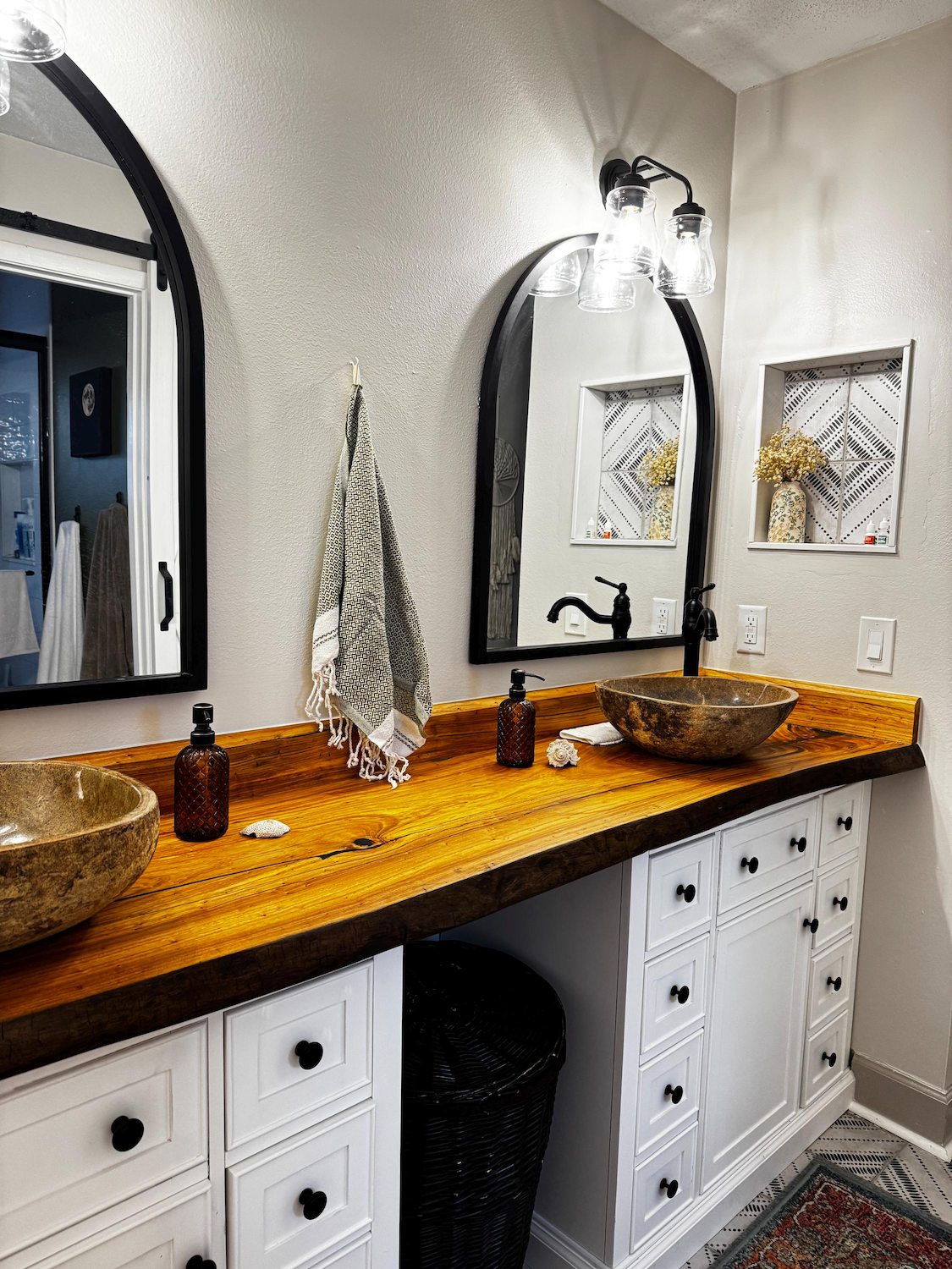 Bathroom with live edge chestnut wooden vanity, round sinks, and white cabinets.