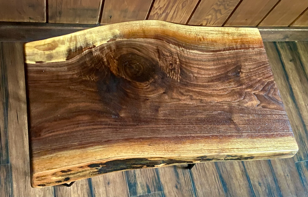 Live edge walnut wood slab coffee table with a natural grain pattern on a wooden surface