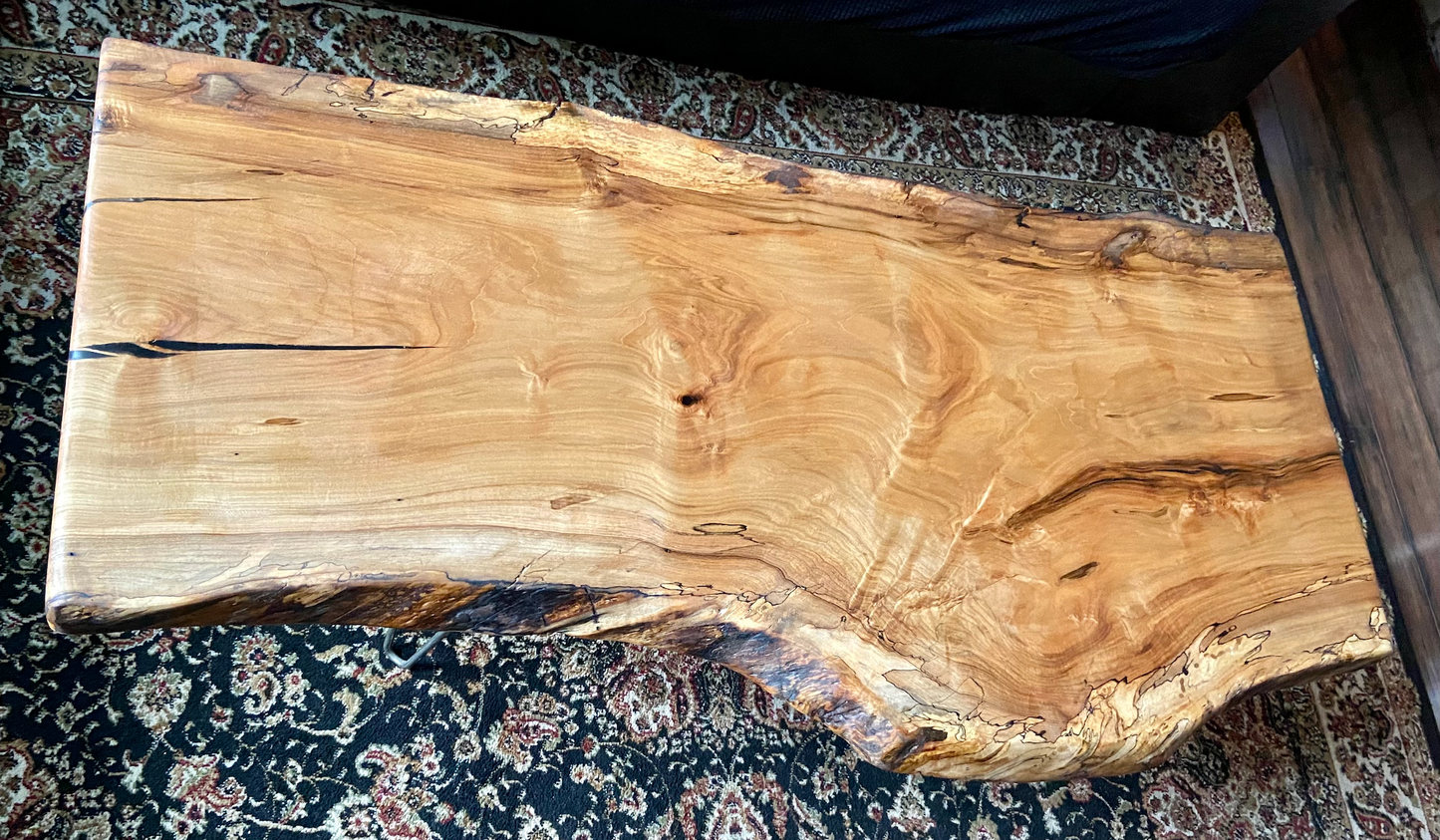 Live edge spalted ambrosia maple wood slab coffee table on a patterned rug. 