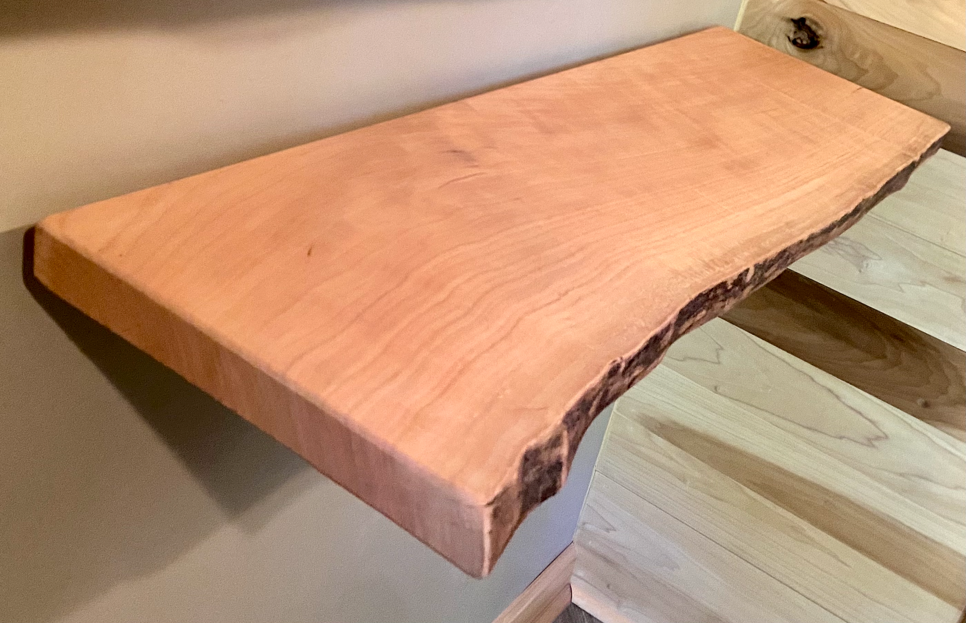 Live edge sycamore wood floating shelf mounted on a wall, showcasing natural grain and rustic edge detail.