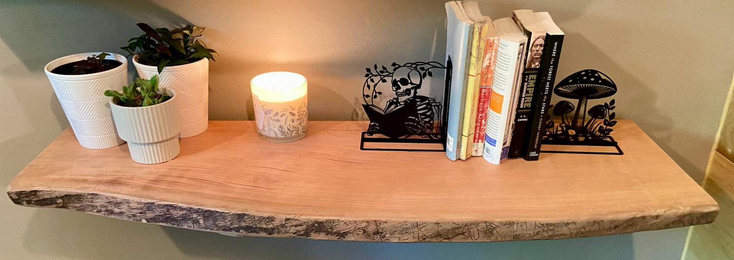 Rustic live edge sycamore shelf styled with books, metal bookends, potted plants, and a candle — ideal for modern farmhouse or nature-inspired interiors.