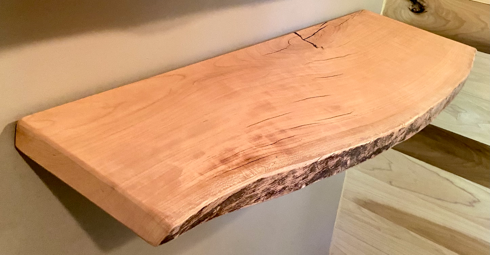 Live edge sycamore wood floating shelf mounted on a wall, showcasing natural grain and rustic edge detail.