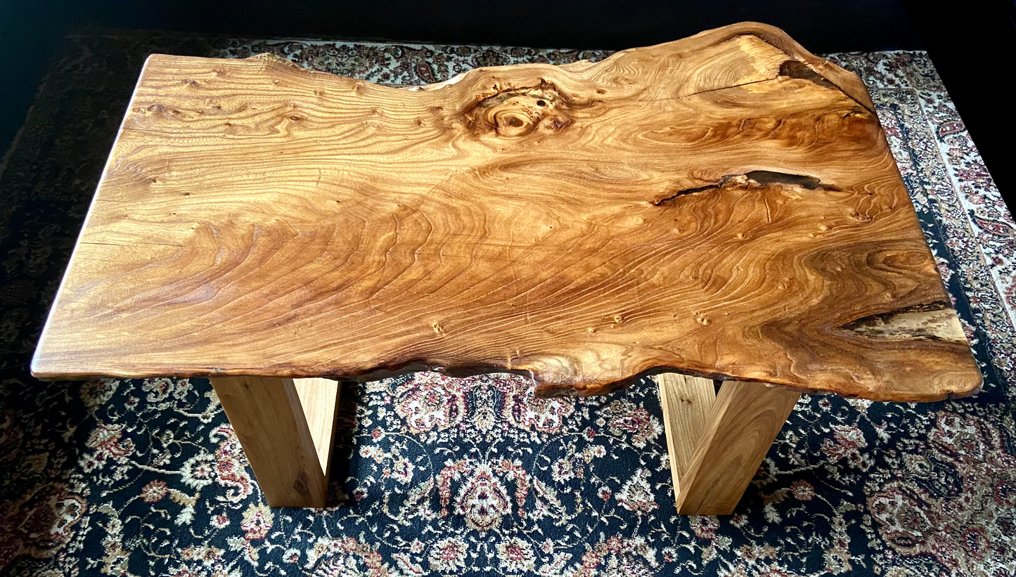Live edge chestnut wood coffee table with a natural, rustic finish on a patterned rug.