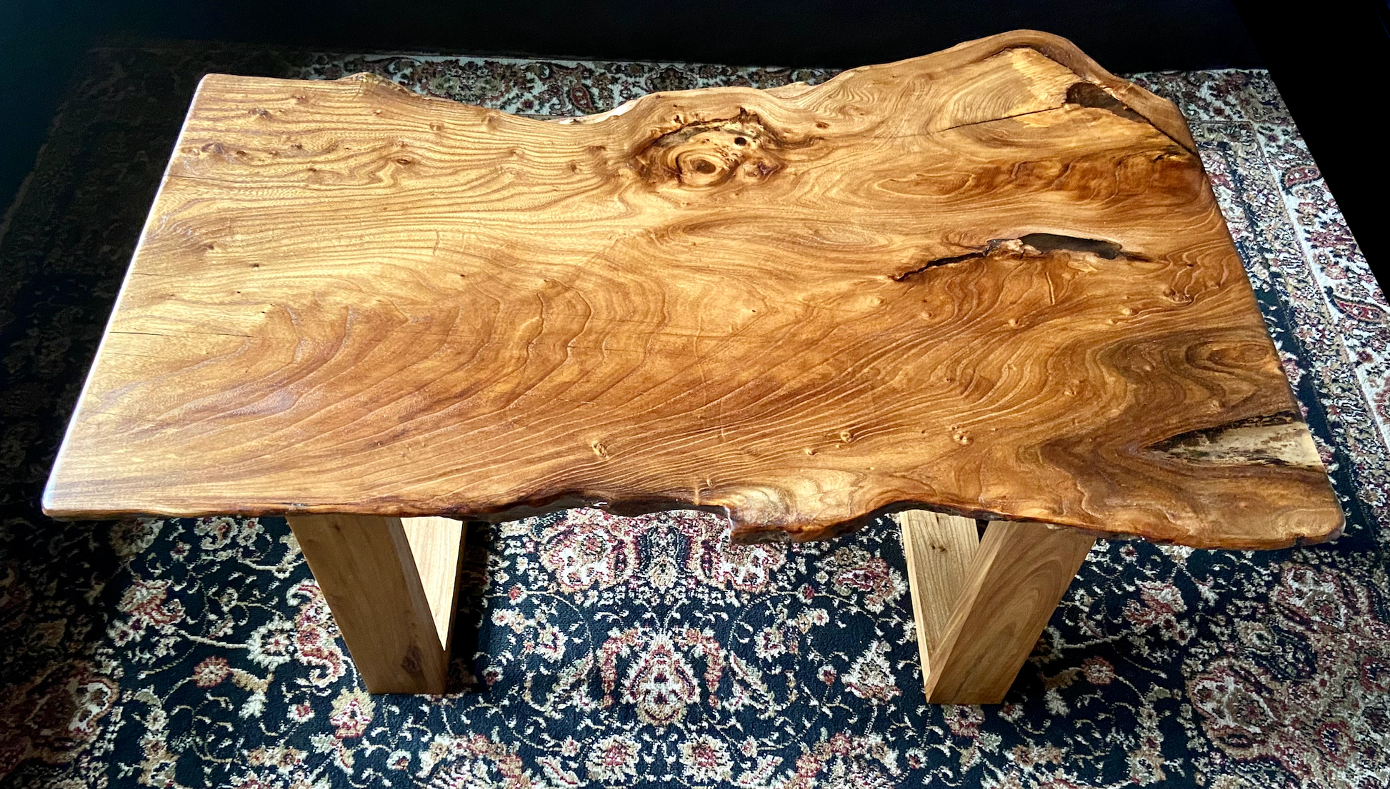 Live edge chestnut wood coffee table with a natural, rustic finish on a patterned rug.