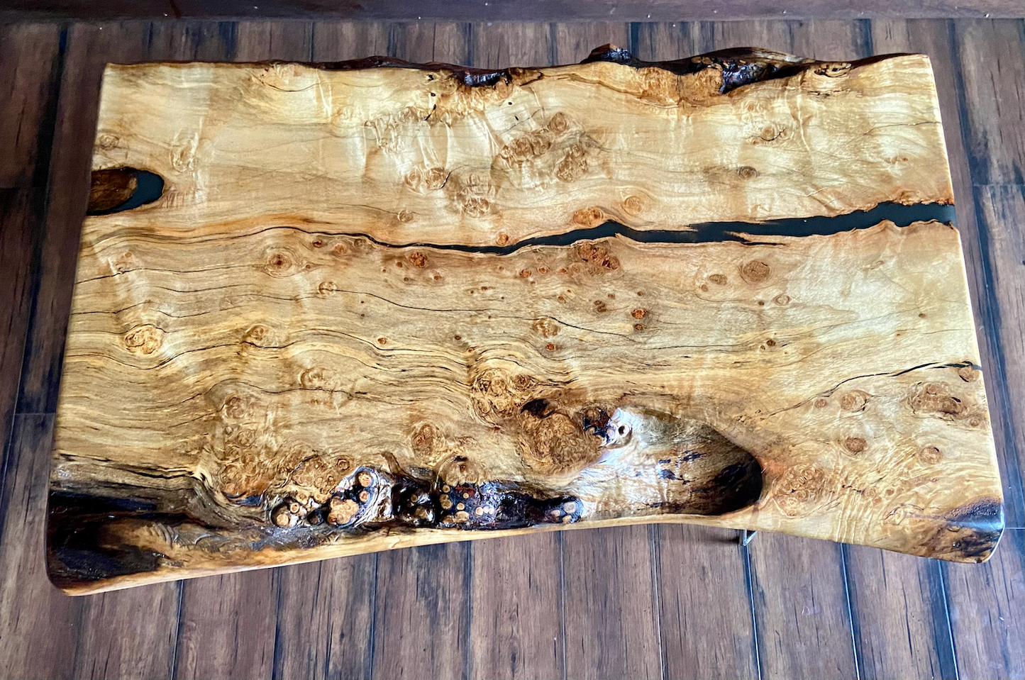 Live edge spalted ambrosia maple wood slab coffee table with a natural, rustic finish on a wooden floor.