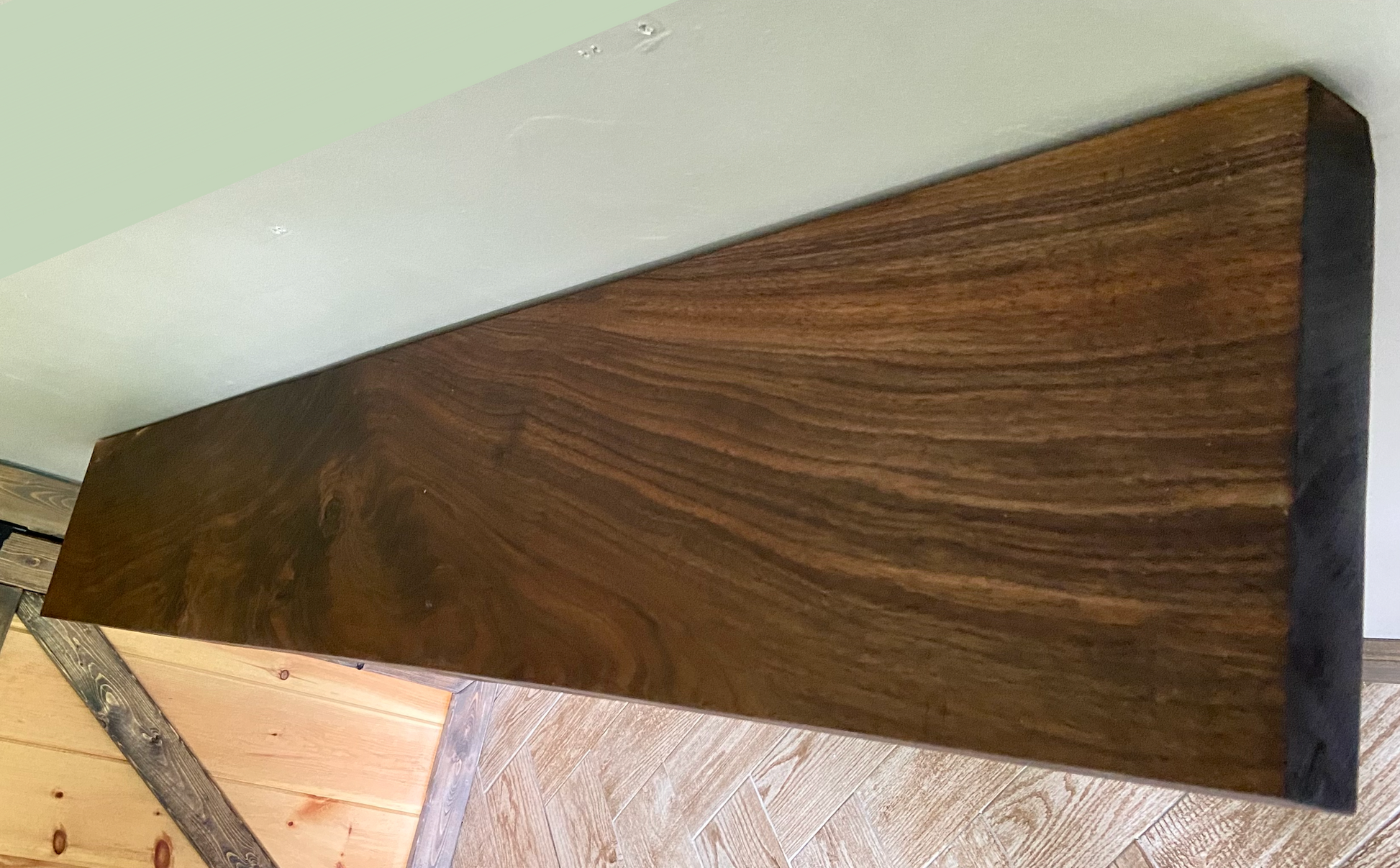 Front view of a handcrafted straight edge black walnut floating shelf mounted on a wall, displaying decorative items. Close-up of the solid black walnut wood grain, highlighting the shelf’s smooth finish. Side angle showcasing the shelf’s thickness and sturdy wall brackets.