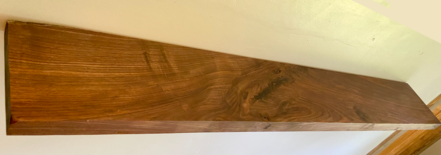 Front view of a handcrafted straight edge black walnut floating shelf mounted on a wall, displaying decorative items. Close-up of the solid black walnut wood grain, highlighting the shelf’s smooth finish. Side angle showcasing the shelf’s thickness and sturdy wall brackets.