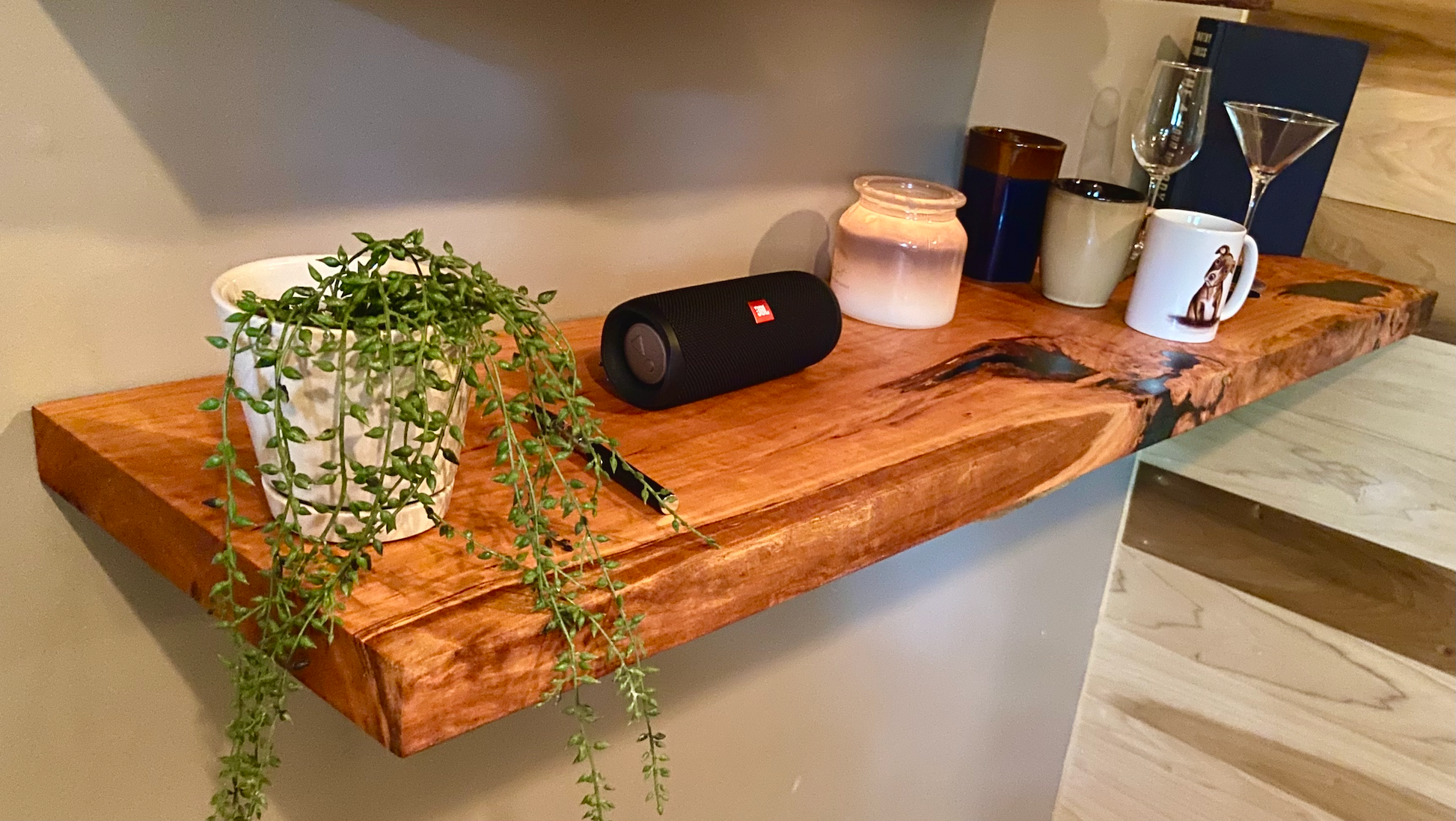 Front view of a handcrafted cherry floating shelf mounted on a wall, displaying decorative items. Close-up of the solid cherry wood grain, highlighting the shelf’s smooth finish. Side angle showcasing the shelf’s thickness and sturdy wall brackets.