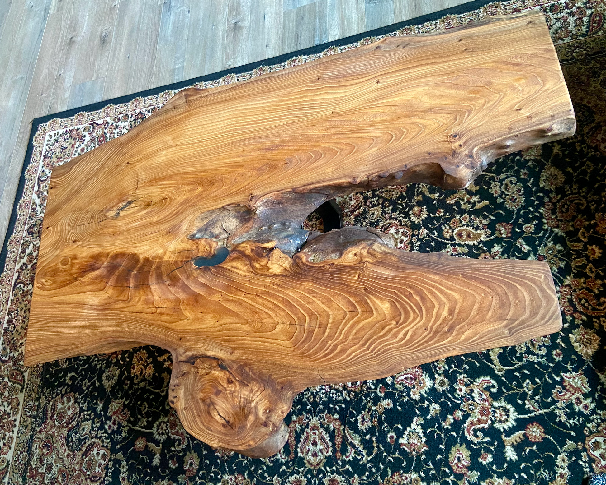 Live edge chestnut wood coffee table with a natural, rustic surface on a patterned rug.