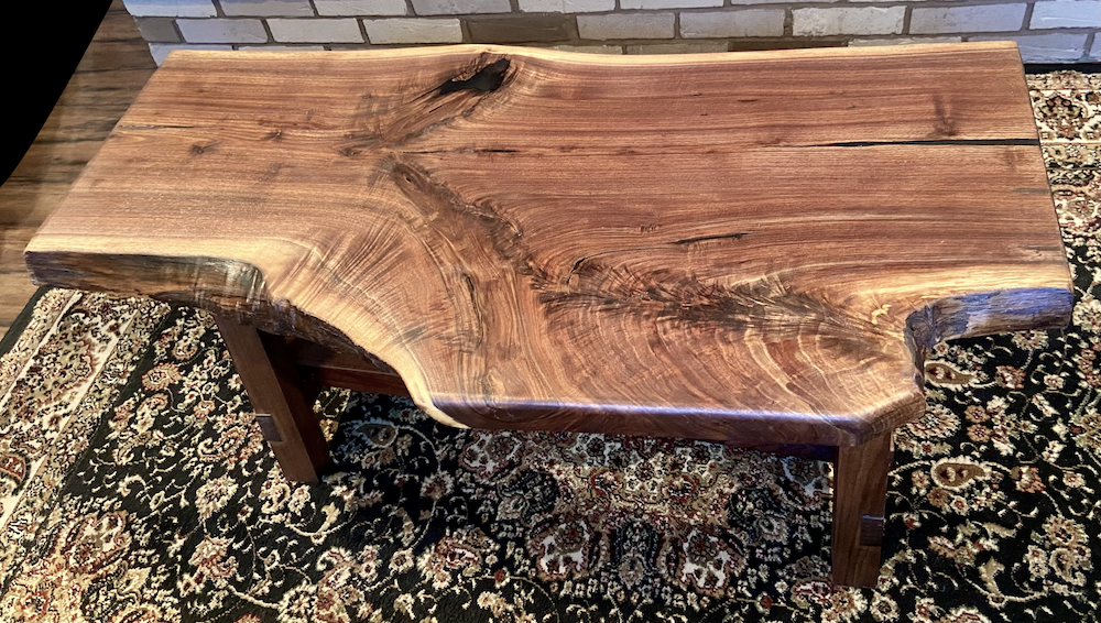 Live edge walnut wood slab coffee table with a natural edge design on a patterned rug.
