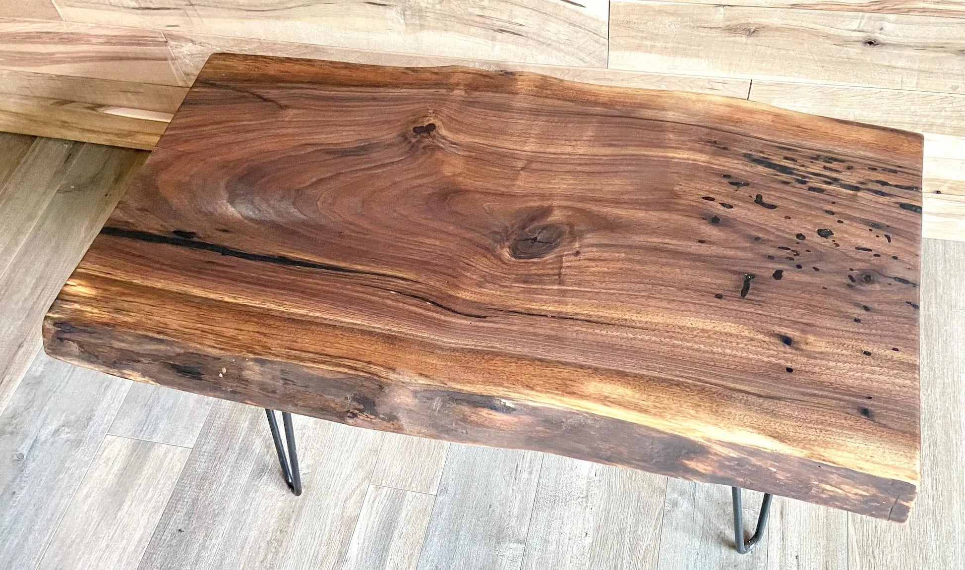 Live edge walnut wood slab coffee table with a rustic design on a wooden floor